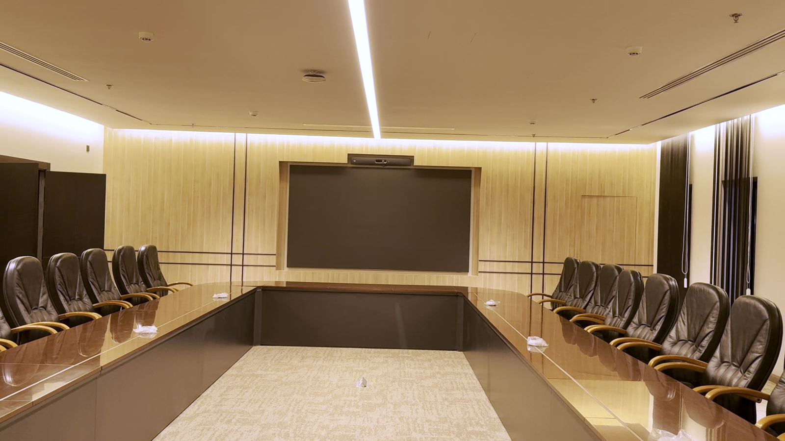 Executive boardroom with wood-slat wall cladding and cove lighting
